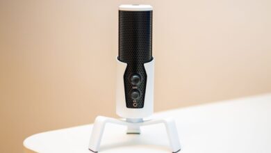 Minimalist close-up of a sleek black microphone on a modern white table, ideal for podcasts and broadcasting.