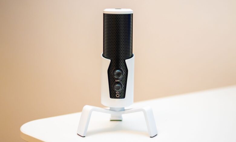 Minimalist close-up of a sleek black microphone on a modern white table, ideal for podcasts and broadcasting.