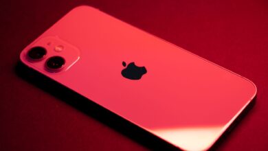Close-up of a red smartphone with dual lenses on a red backdrop, highlighting sleek design and technology.