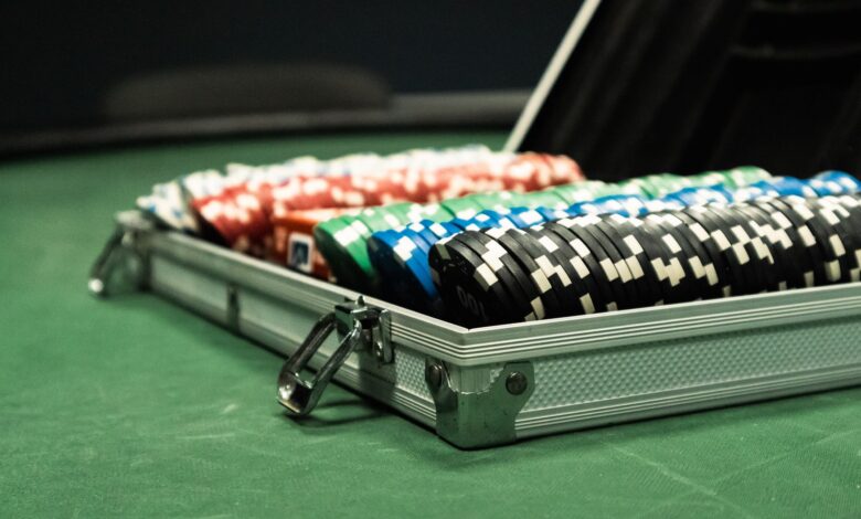 Close-up of a poker set with colorful chips arranged in a briefcase on a green table.