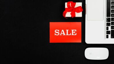 Flat lay of a laptop, gift box, and sale sign for online shopping promotion.