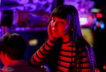 Young woman in neon lights at an arcade, enjoying a vibrant gaming experience.