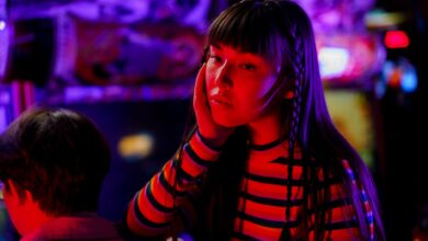 Young woman in neon lights at an arcade, enjoying a vibrant gaming experience.