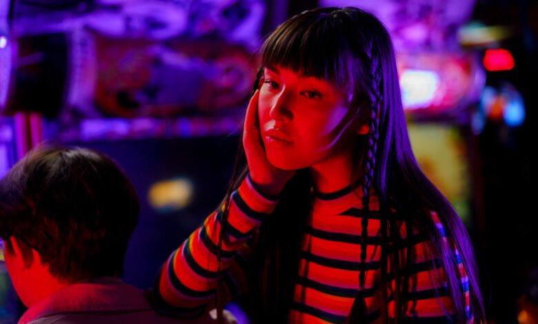 Young woman in neon lights at an arcade, enjoying a vibrant gaming experience.