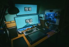 A sleek gaming desk setup featuring dual monitors, keyboard, and gaming PC in a dimly lit home office.