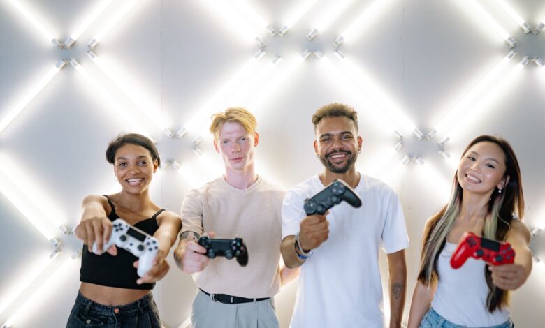 Four friends holding game controllers and smiling, enjoying time together indoors.