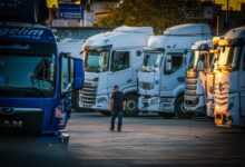 A man walks among parked trucks at sunset in an industrial area, creating a serene yet busy scene.