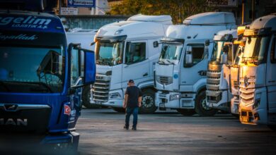 A man walks among parked trucks at sunset in an industrial area, creating a serene yet busy scene.