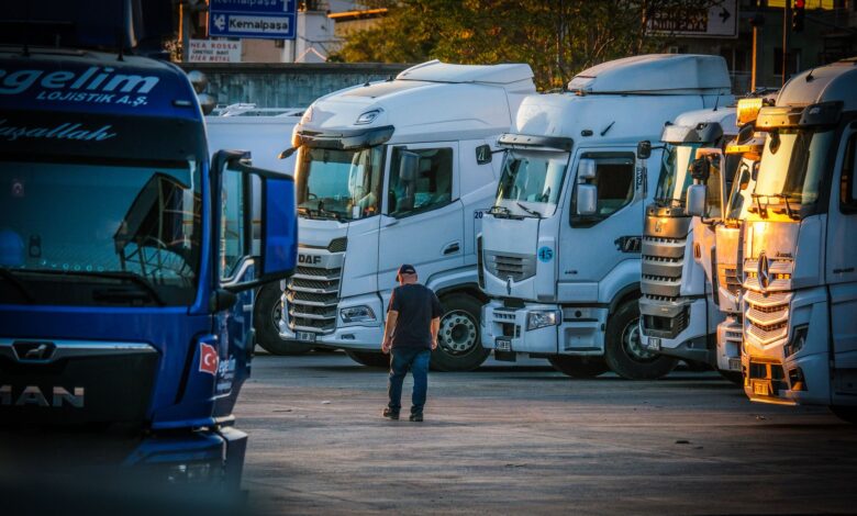 A man walks among parked trucks at sunset in an industrial area, creating a serene yet busy scene.