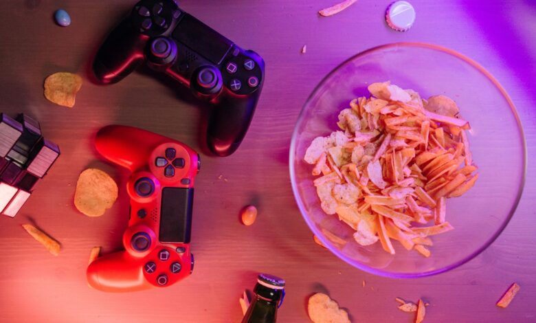 Overhead view of game controllers and snacks on a table, perfect for a gaming night setup.