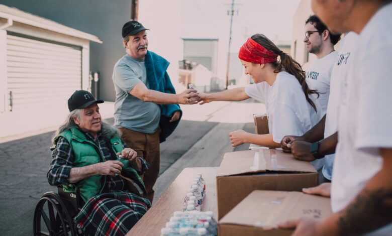 Volunteers distribute water and supplies to people outdoors, promoting community support and kindness.