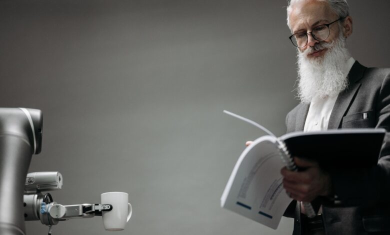 Elderly man reads as a robotic arm holds a coffee cup, showcasing technology integration.