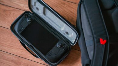 A close-up shot of a gaming console in its case next to a backpack on a wooden floor.