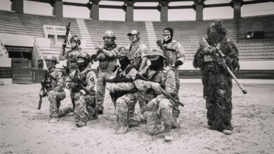 Group of soldiers in tactical gear posing in an arena for a military drill.