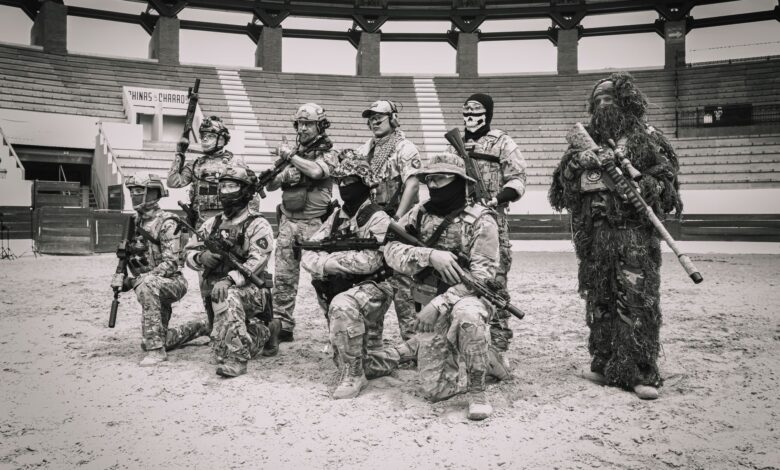 Group of soldiers in tactical gear posing in an arena for a military drill.