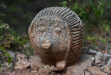 Artistic stone hedgehog sculpture in outdoors with nature background.
