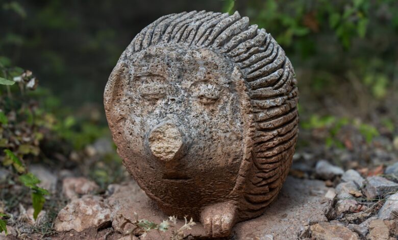 Artistic stone hedgehog sculpture in outdoors with nature background.