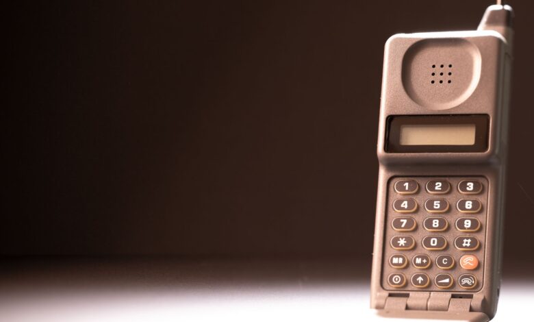 Vintage mobile phone with keypad and antenna on a dark background, emphasizing retro technology.