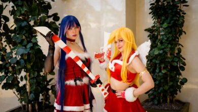 Two cosplayers in Christmas-themed costumes with props at an anime convention in Orlando.