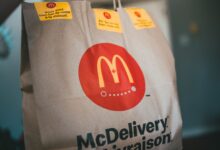 Paper packet with tasty fresh hot fast food on blurred background in restaurant