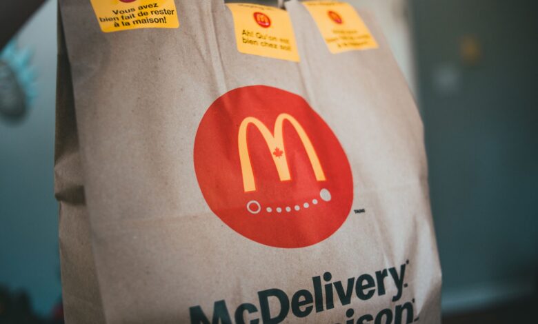 Paper packet with tasty fresh hot fast food on blurred background in restaurant
