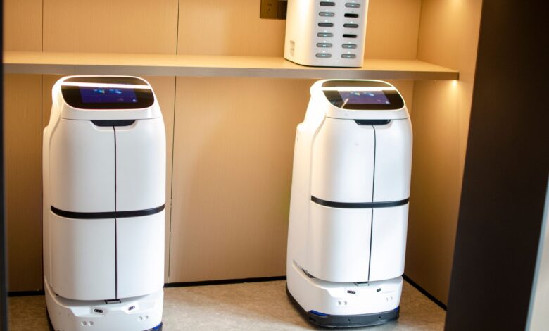 Two white robotic delivery systems located in a modern indoor room with soft lighting.