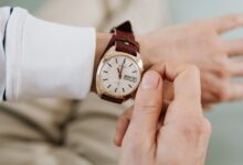 A close-up of a person adjusting a vintage brown leather strap analog wristwatch.