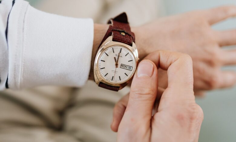 A close-up of a person adjusting a vintage brown leather strap analog wristwatch.