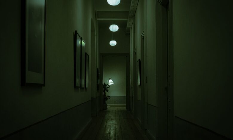 Explore the moody atmosphere of a narrow corridor with green lighting and hanging lamps.