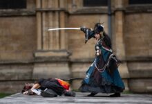 Dramatic outdoor cosplay scene with sword fight and elaborate costumes.