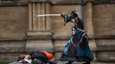 Dramatic outdoor cosplay scene with sword fight and elaborate costumes.