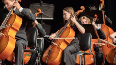 Orchestra cellists performing classical music in an indoor concert setting.