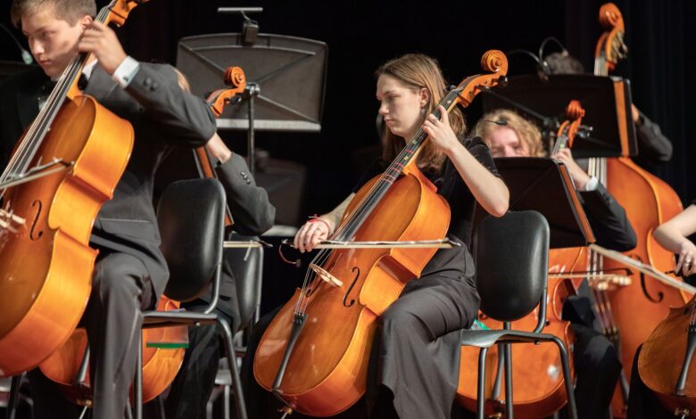 Orchestra cellists performing classical music in an indoor concert setting.