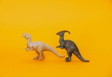 Two dinosaur toy figurines displayed against a vibrant yellow background, fostering imagination and play.