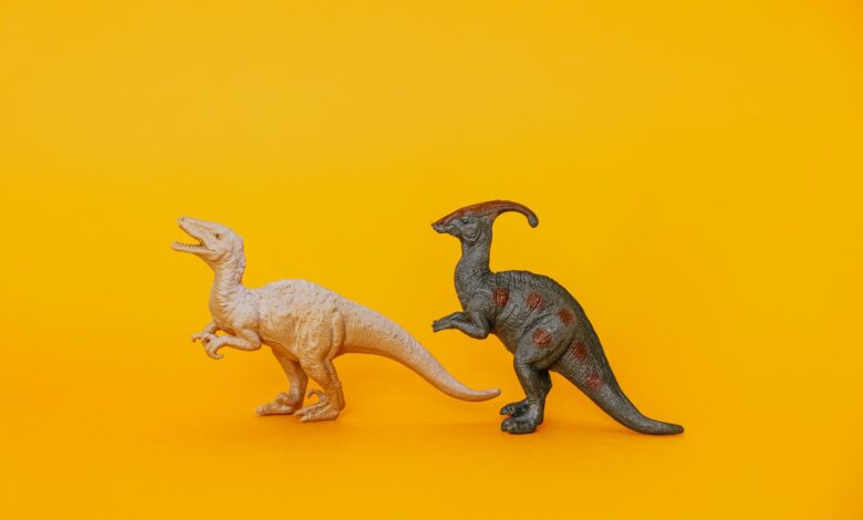 Two dinosaur toy figurines displayed against a vibrant yellow background, fostering imagination and play.