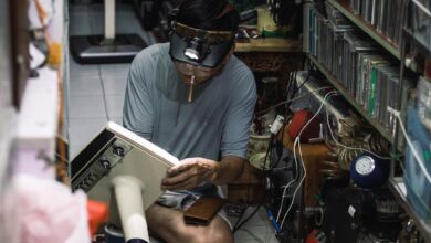 A Vietnamese technician works intently repairing a vintage radio in a cluttered workshop in Hanoi.