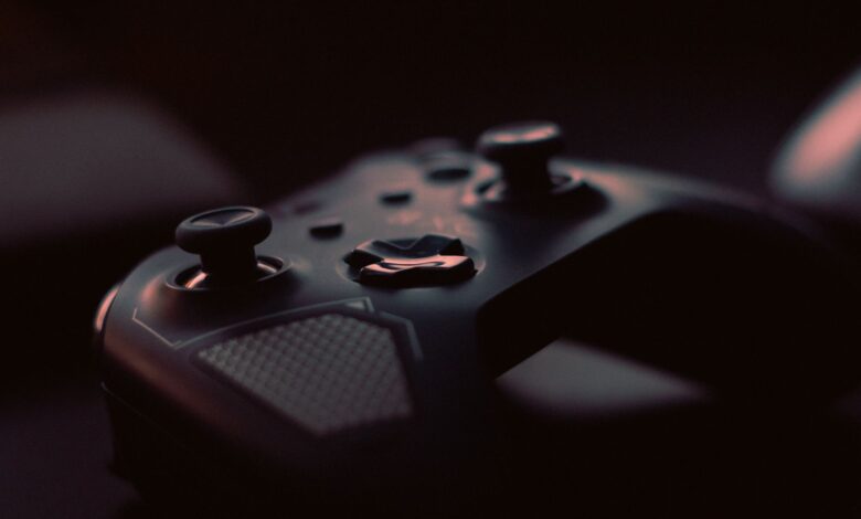 A close-up shot of a game controller in low light, highlighting its design and buttons.