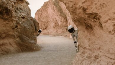Astronauts peek from behind rocks in a fantasy extraterrestrial landscape.