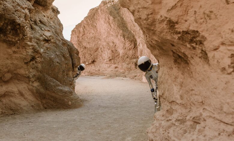 Astronauts peek from behind rocks in a fantasy extraterrestrial landscape.