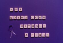 Scrabble tiles with an inspiring quote and a purple ribbon on a purple background.