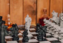 Close-up of a fantasy-themed chess set with intricate black and white pieces in a warm indoor setting.