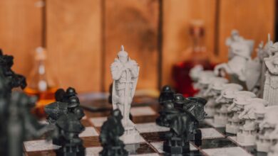 Close-up of a fantasy-themed chess set with intricate black and white pieces in a warm indoor setting.