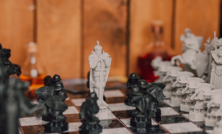 Close-up of a fantasy-themed chess set with intricate black and white pieces in a warm indoor setting.