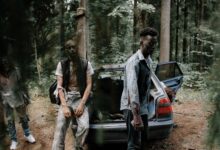 Chilling scene of zombies near an abandoned car in a dense forest.