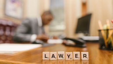 Wooden letter tiles spelling 'LAWYER' on a desk, with blurred office setting in the background.