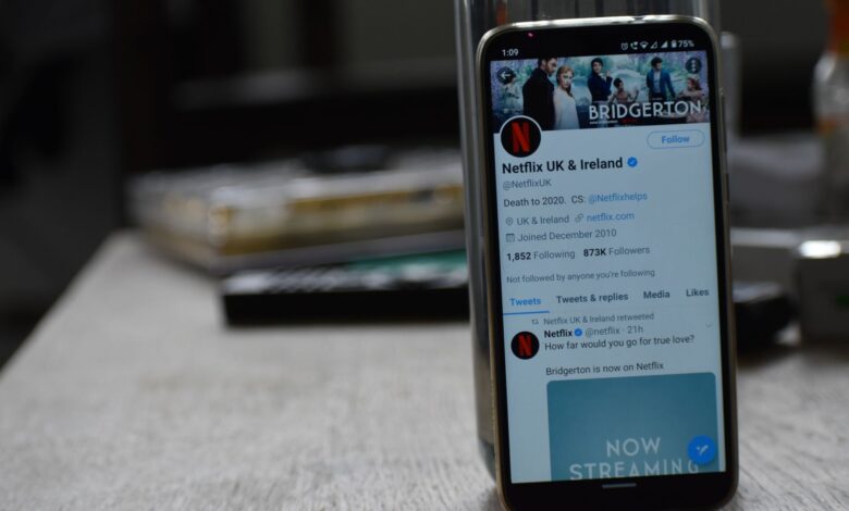 Smartphone showing Netflix's Twitter page on a wooden table.