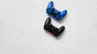 Blue and black PlayStation controllers on a white speckled surface captured from above.