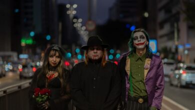 A trio in Halloween-themed cosplay walking through a bustling city street at night.