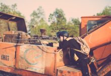 Person engaging in realistic outdoor play with a toy sniper rifle on industrial machinery.