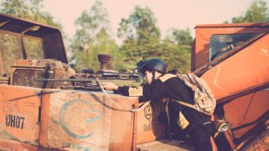 Person engaging in realistic outdoor play with a toy sniper rifle on industrial machinery.